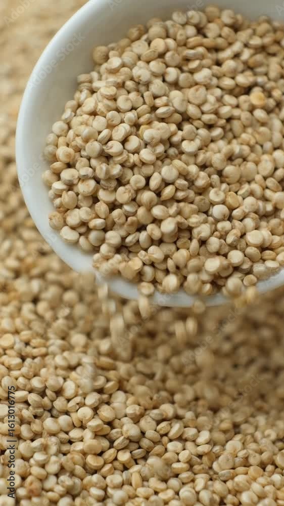 White quinoa pouring out of a spoon, macro slow motion vertical White quinoa pouring out of a spoon, macro slow motion vertical