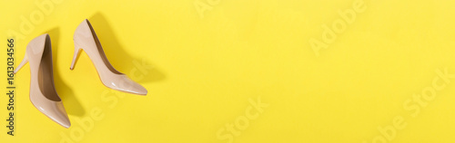Classic beige women's shoes with medium heels on a yellow background. The concept of sales and advertising. flatly. From above.