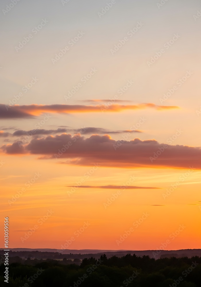 Fototapeta premium Dramatic sunset with layered clouds and vibrant orange sky at twilight time