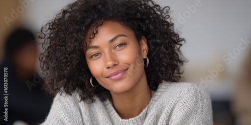 Smiling young african female in cozy sweater with curly hair and gold hoop earrings