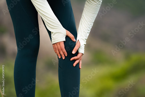 Принти на полотні Woman holding knee in pain after outdoor workout, close-up of legs in sportswear