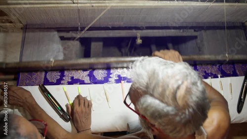 Top view of artisan weaving intricate Banarasi silk fabric using handloom tools in Varanasi, India. Detailed textile work in traditional craftsmanship.