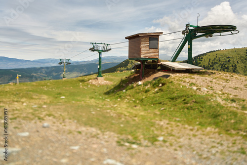 Landscape at the top of a mountain in summer with an empty chairlift with part of the sky out of focus and part of the ground out of focus               