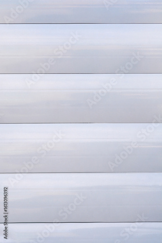 A simple, minimalist shot captures horizontal parallel lines of a closed, light-colored window blind or shutter