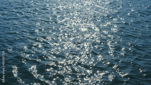 Sparkling sunlight shimmering on ocean waves. Natural sea ripple surface background for environmental concepts.