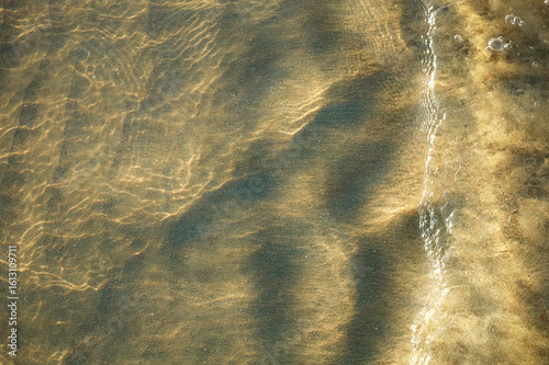 Fototapeta Naklejka Na Ścianę i Meble -  The beach reflects the sunlight on the waves and wet sand. It appears the sand under the water