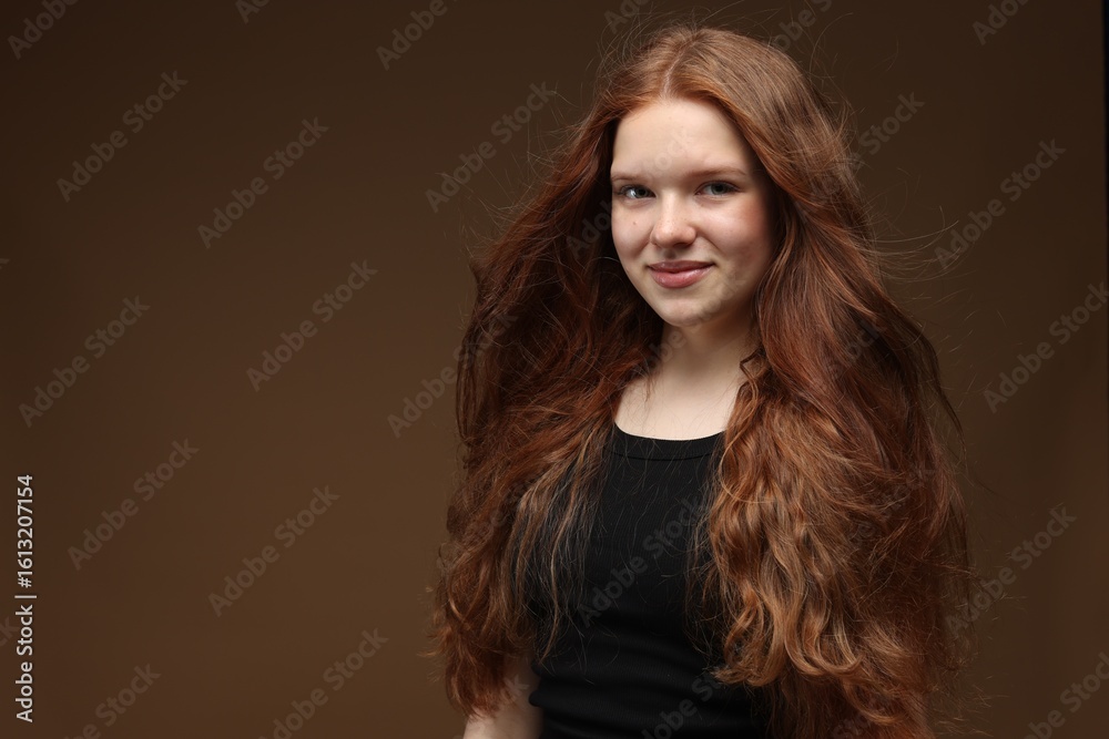 Naklejka premium Portrait of beautiful teenage girl with healthy wavy hair on brown background. Space for text