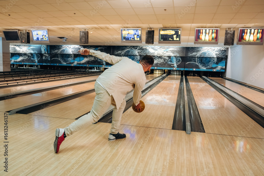Fototapeta premium Running and throwing a ball. Man is playing bowling indoors