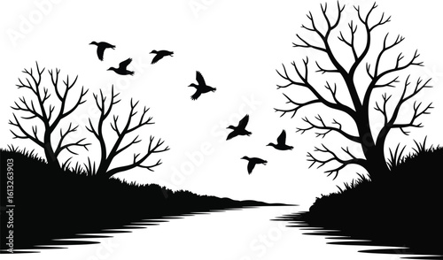 Black silhouette of bare trees and flying birds over a reflective water path in a stark landscape silhouette
