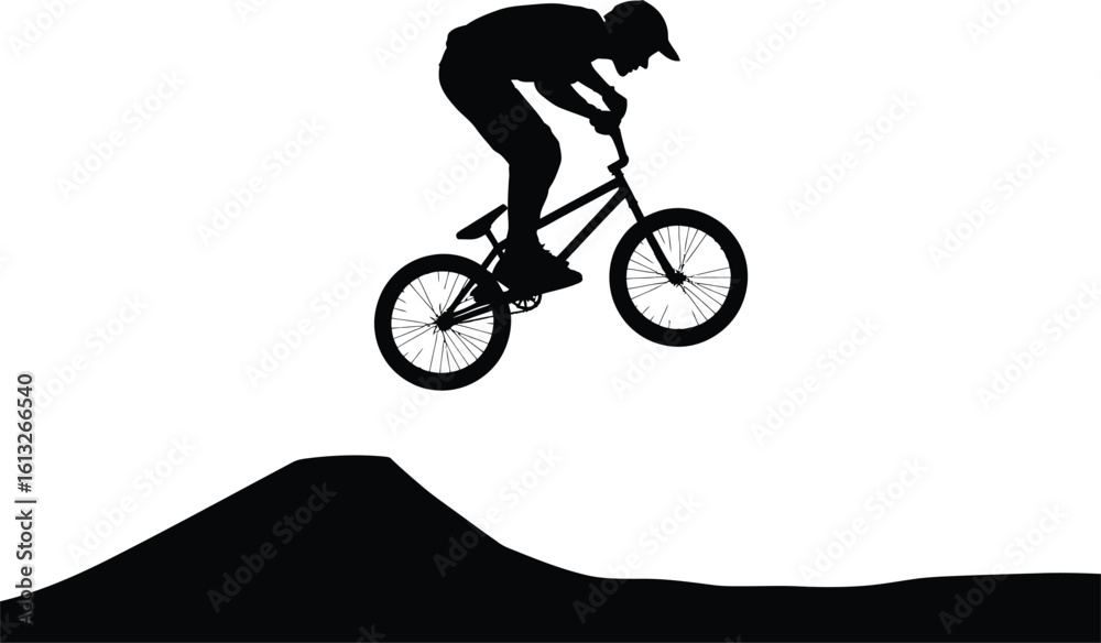 Fototapeta premium Dynamic silhouette of a bmx rider performing a jump over a dirt ramp in mid air action