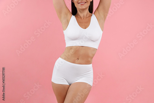 Fit woman with perfect body on pink background, closeup
