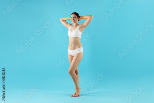 Beautiful woman in underwear on light blue background