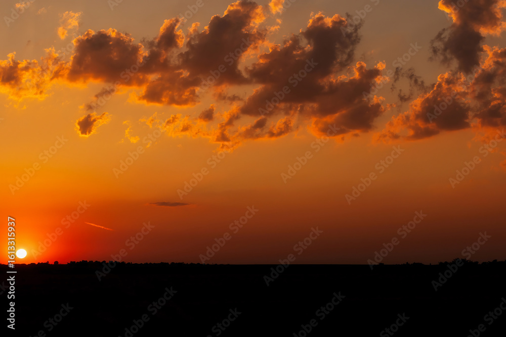 Obraz premium Colorful Sunset Sky Over Nature Landscape with Silhouetted Trees and Clouds