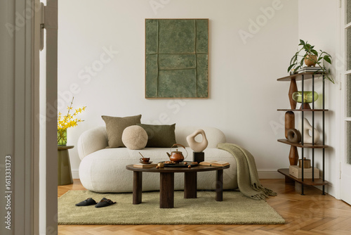 Modern interior with graphic mock up wall art, sculptural decorations, bouclé sofa and green accents. A curated mix of textures and form.