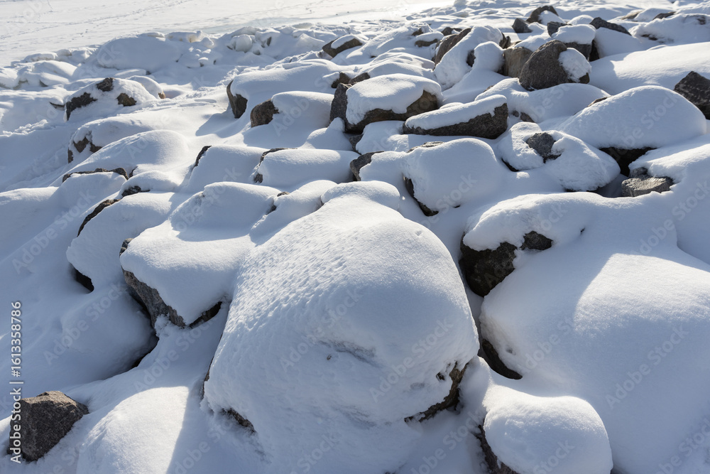 Obraz premium Snow-Covered Rocky Surface Under Bright Sunlight in Winter