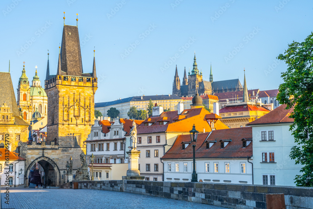 Fototapeta premium Dawn breaks over Charles Bridge in Prague, illuminating the stunning architecture and historical landmarks. The quiet river Vltava reflects the warm hues of morning light.
