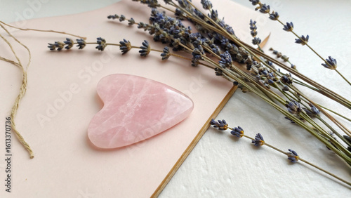 Rose quartz Gua Sha tool with lavender sprigs for spa, wellness, and self-care routines