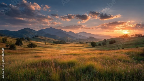 Golden sunset over a grassy valley with mountains