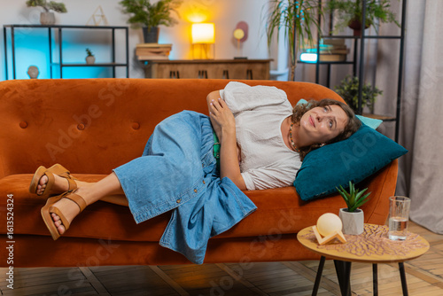 Sick ill woman lady suffering from period cramps, painful stomach ache on couch at home. Girl holding belly, feeling abdominal menstrual pain. Abdominal pain gastritis diarrhea indigestion. Lifestyles