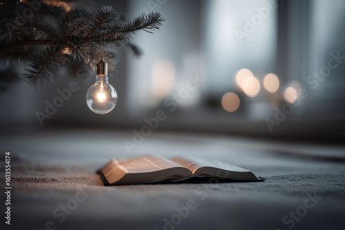 minimalist composition featuring single ultrabright bulb hanging from christmas tree with bible placed underneath