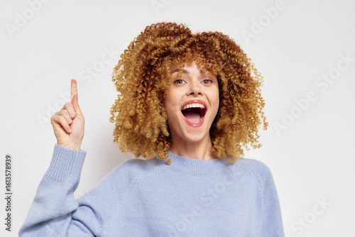 Принти на полотні Young woman with curly hair smiling joyfully against a plain white background, w