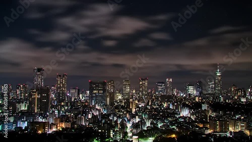 Wallpaper Mural Nighttime urban skyline under cloudy sky with stars. Serene cityscape with illuminated buildings at night. Wide-angle view of resting metropolis under night clouds. Torontodigital.ca