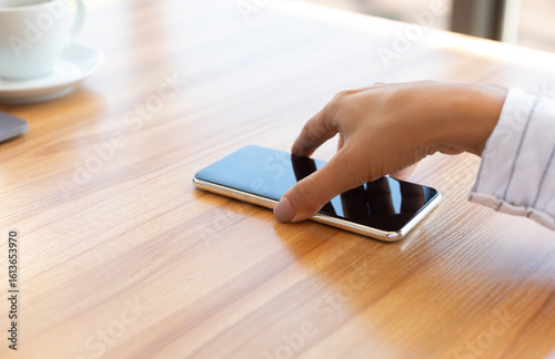 Notification. Closeup of lady taking cell phone off desktop or laying it down on table