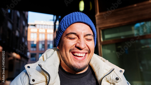 Young man wearing knit hat laughing during sunny day