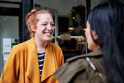 Happy woman looking at female friend outside cafe