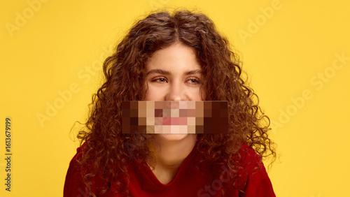 Surreal collage. Portrait of happy curly-haired girl on yellow background with pixelated mouth. Concept of filtered speech, emotional masking, youth expression, and censorship.