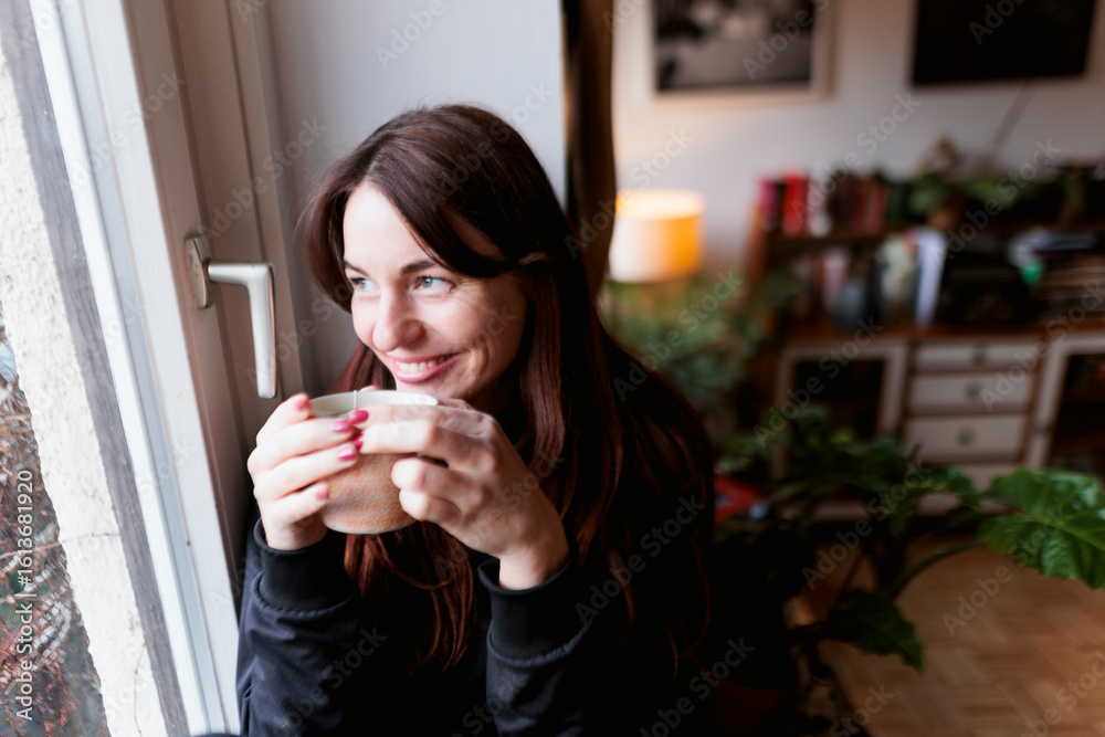 Brunette woman drinking tea by the window Brunette woman drinking tea by the window