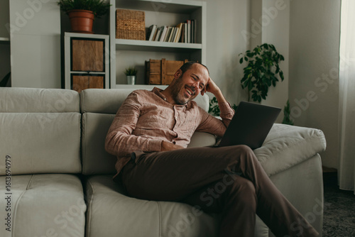 Smiling man watching movie on laptop at home