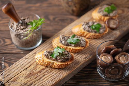 Toast or bruschetta with mushroom spread on wooden board on the table.