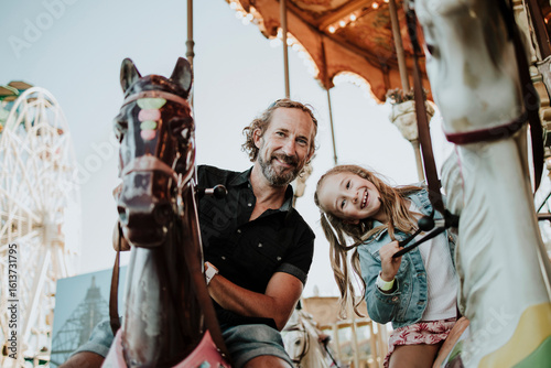 Father and daughter enjoying carousel ride at amusement park