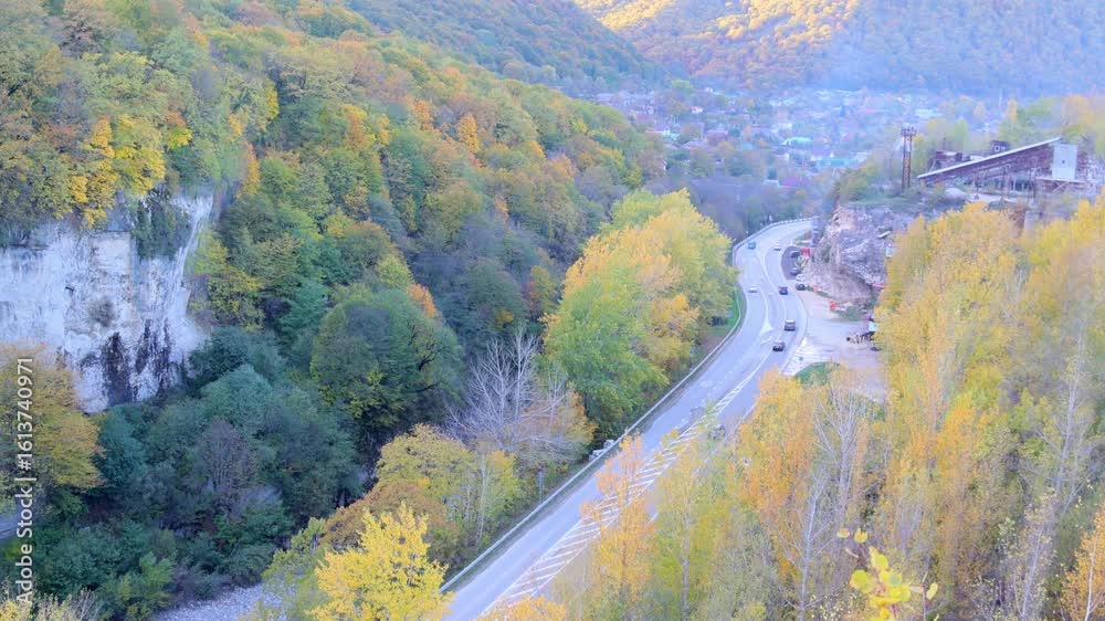 autumn landscape with a road in the mountains with cars driving on the background of wooded hills view from a height, 4k video