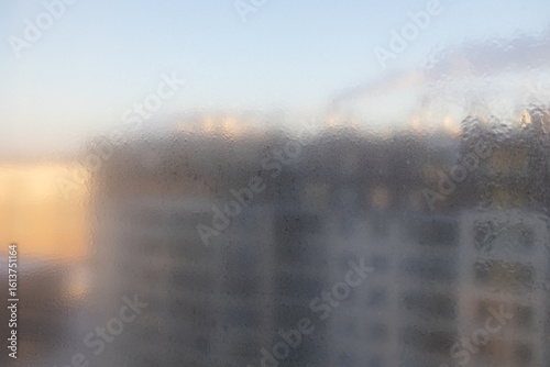 Window with a blurry view of a building. The window is foggy and the building is tall