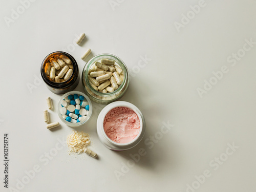 Top view of assorted health supplements including pills, capsules and colorful powders on clean white background flat lay