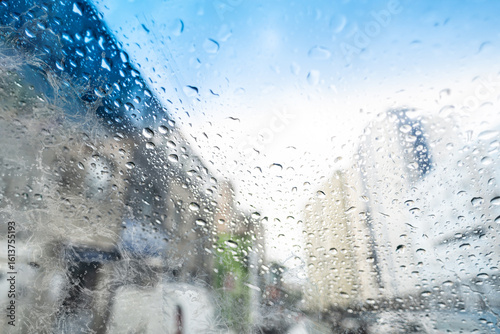 Blurred view with rain drops on the glass of a car on a street during traffic movement. Texture.