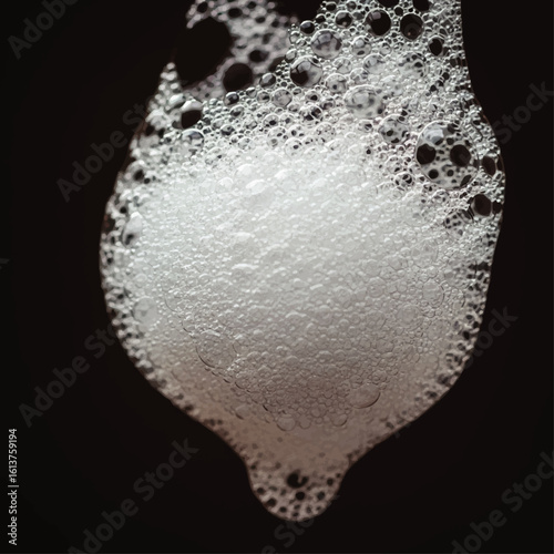 Close-up of a dynamic, foamy substance, with bubbles in various sizes, against a dark background.