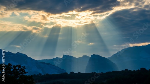 Sunbeams breaking through clouds over blue mountain range