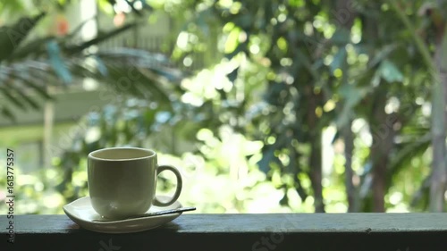 A cup of coffee sits on a table by a window with a garden view