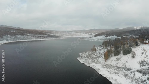 Wallpaper Mural Aerial view of a dark, serene lake contrasting with the snow-covered hills and trees, creating a picturesque winter landscape, Ulagan, Altai Republic, Russia. Torontodigital.ca