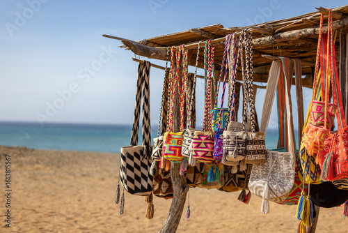 Colorful Wayuu Bags Hanging Under Rustic Wooden Shelter in Desert Landscape