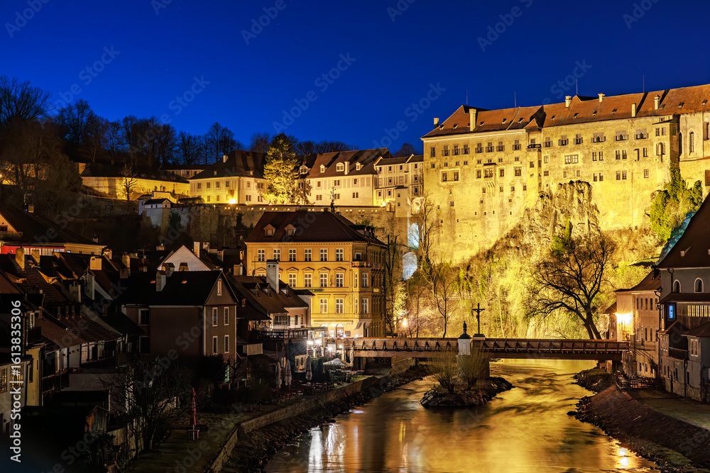 Obraz premium Historic castle above illuminated town at night with clear blue sky