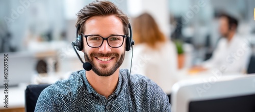 Close-up of a smiling male call center staff wearing a headset and glasses in a bright modern office, ideal for customer support, tech service, or business communication visuals