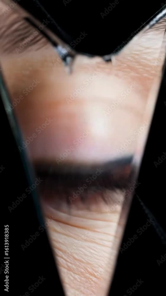 Reflected Gaze: Blinking Eye Seen Through Shard of Mirror in Darkness - A blinking brown eye captured through a sharp triangular mirror shard, reflecting mystery, depth, and fragmented perception.