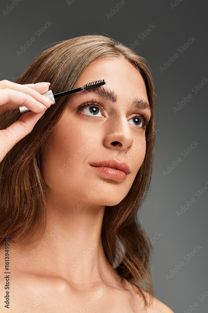Fototapeta premium Beauty routine in action as a young woman perfects her eyebrows with a wand