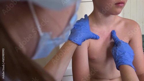 The physician is examining the boy for symptoms of smallpox-like illness.