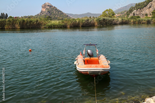 Fototapeta Naklejka Na Ścianę i Meble -  A small inflatable boat moored on the calm Dalyan River in Turkey