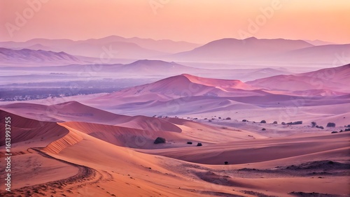 Serene Desert Landscape: Pink and Orange Sand Dunes with Distant Mountains at Sunset or Sunrise.